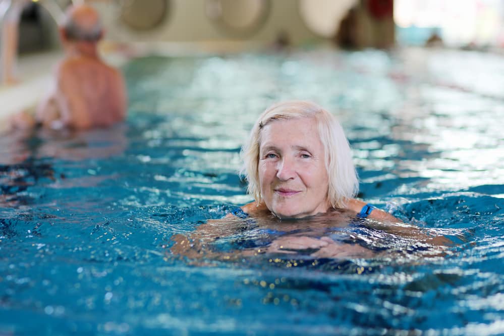Smiling senior woman swimming in pool