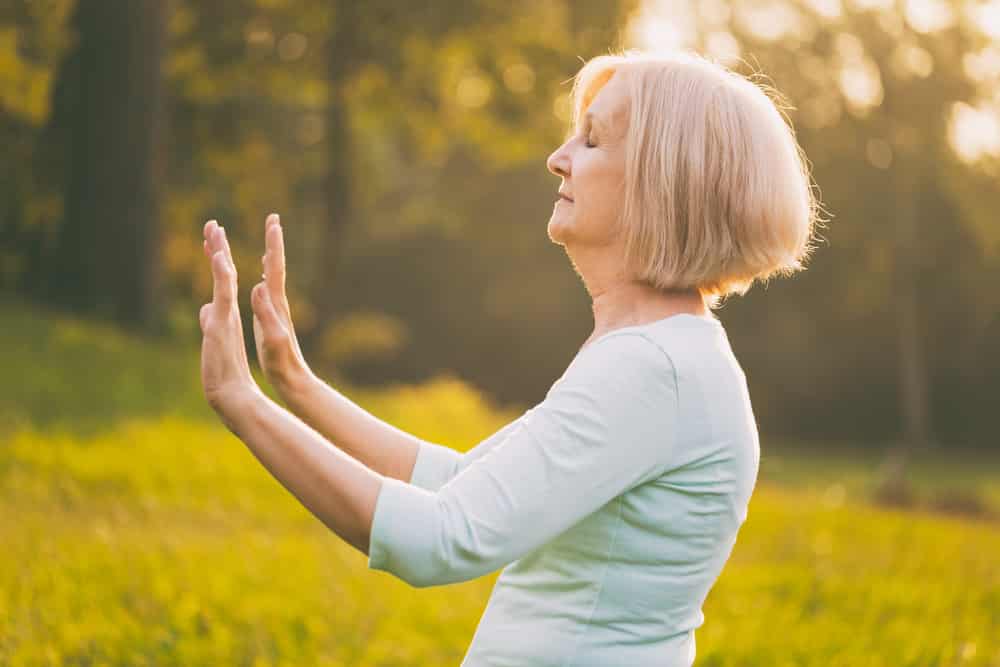 Senior woman in the early morning, outside, performing tai chi