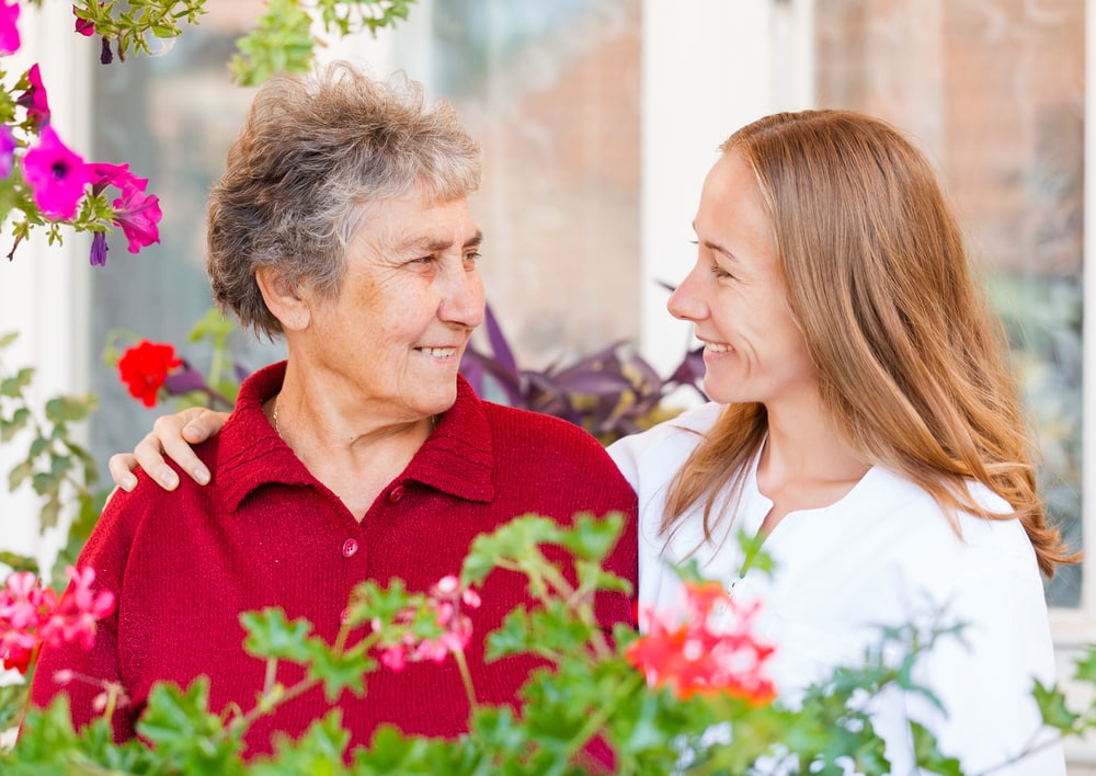 Smiling young woman and older woman talking, flowers surrounding