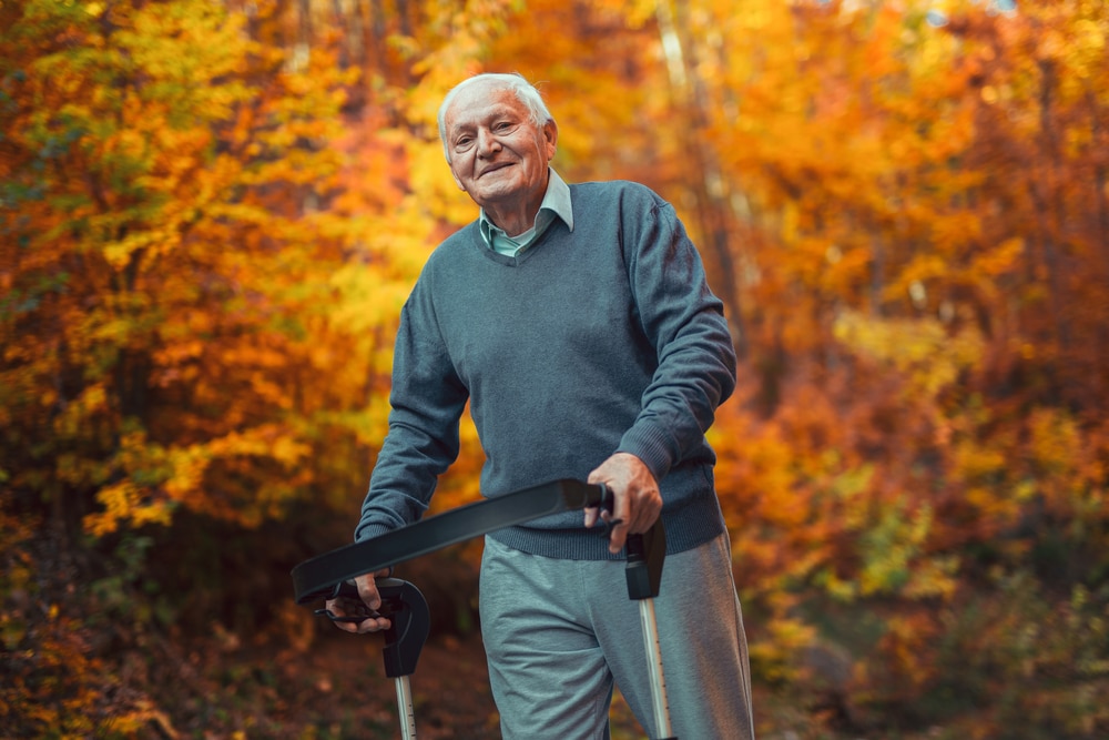 Senior man walking outside with assisitive device in autumn, beautiful leaves