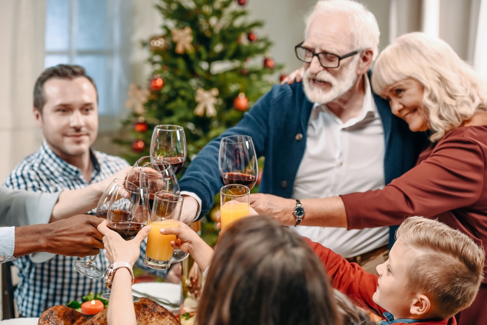 Senior couple smiling and toasting with family at Christmas