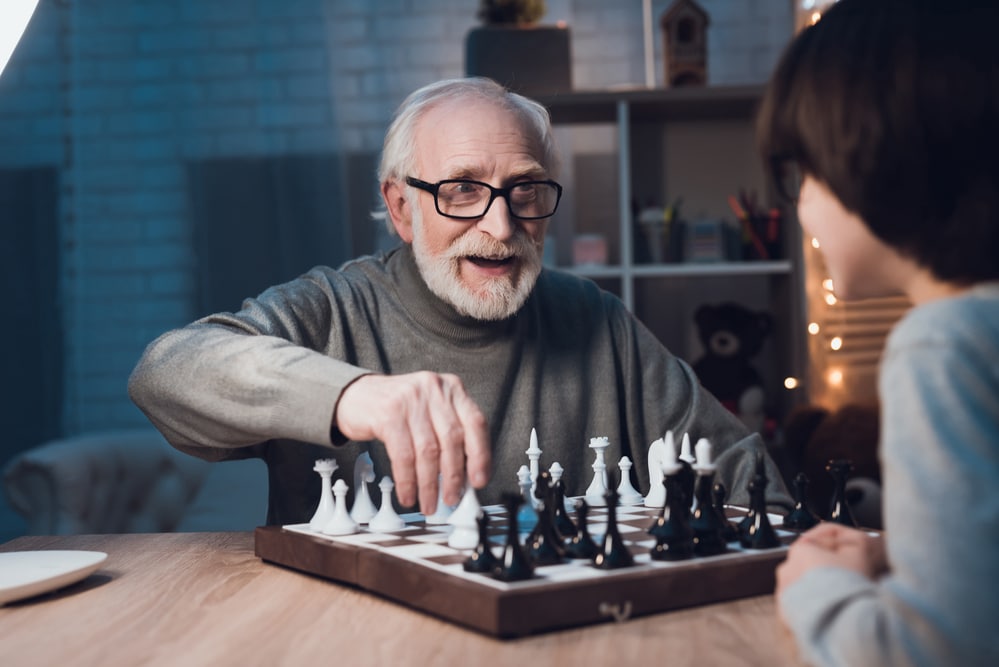 Senior man playing chess with grandson
